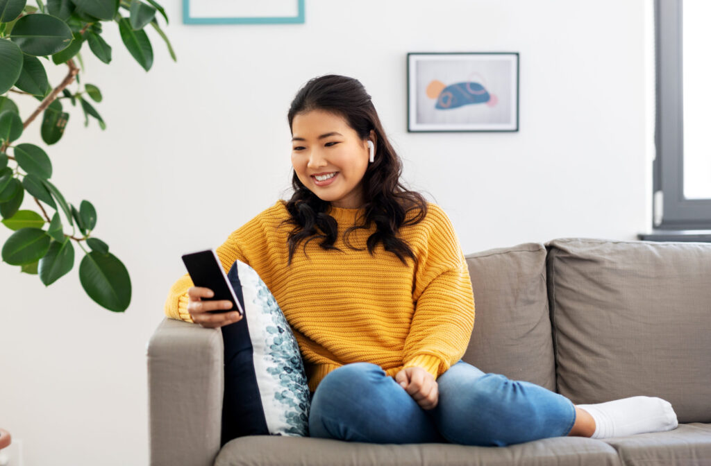 Asian woman with earphones and smartphone at home