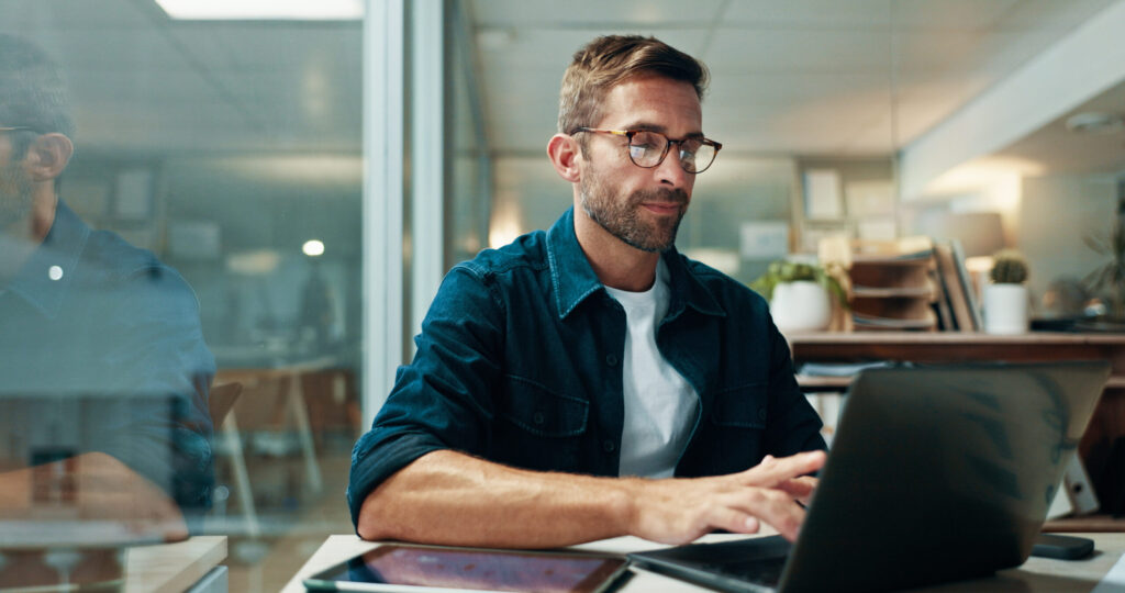 Businessman, typing and laptop in office with night, overtime and writer at publishing agency. proposal, journalist professional and deadline for news article, reporter and employee in workplace