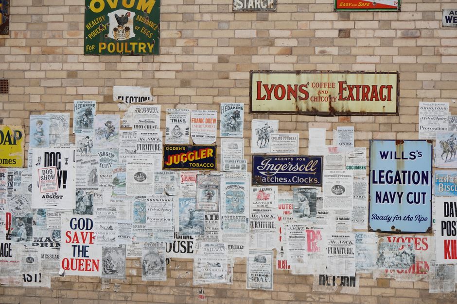 historic and modern advertising posters on a city wall